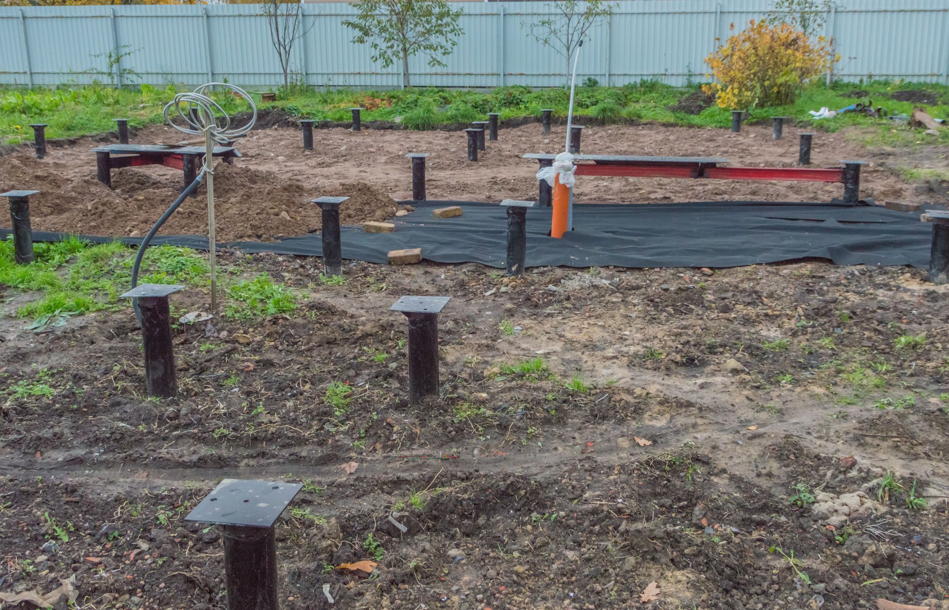 Construction site with metal posts and black tarp on the ground