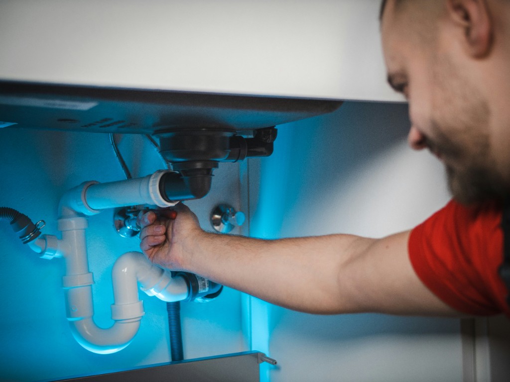 Plumber tightening valve fittings on water pipes with a wrench
